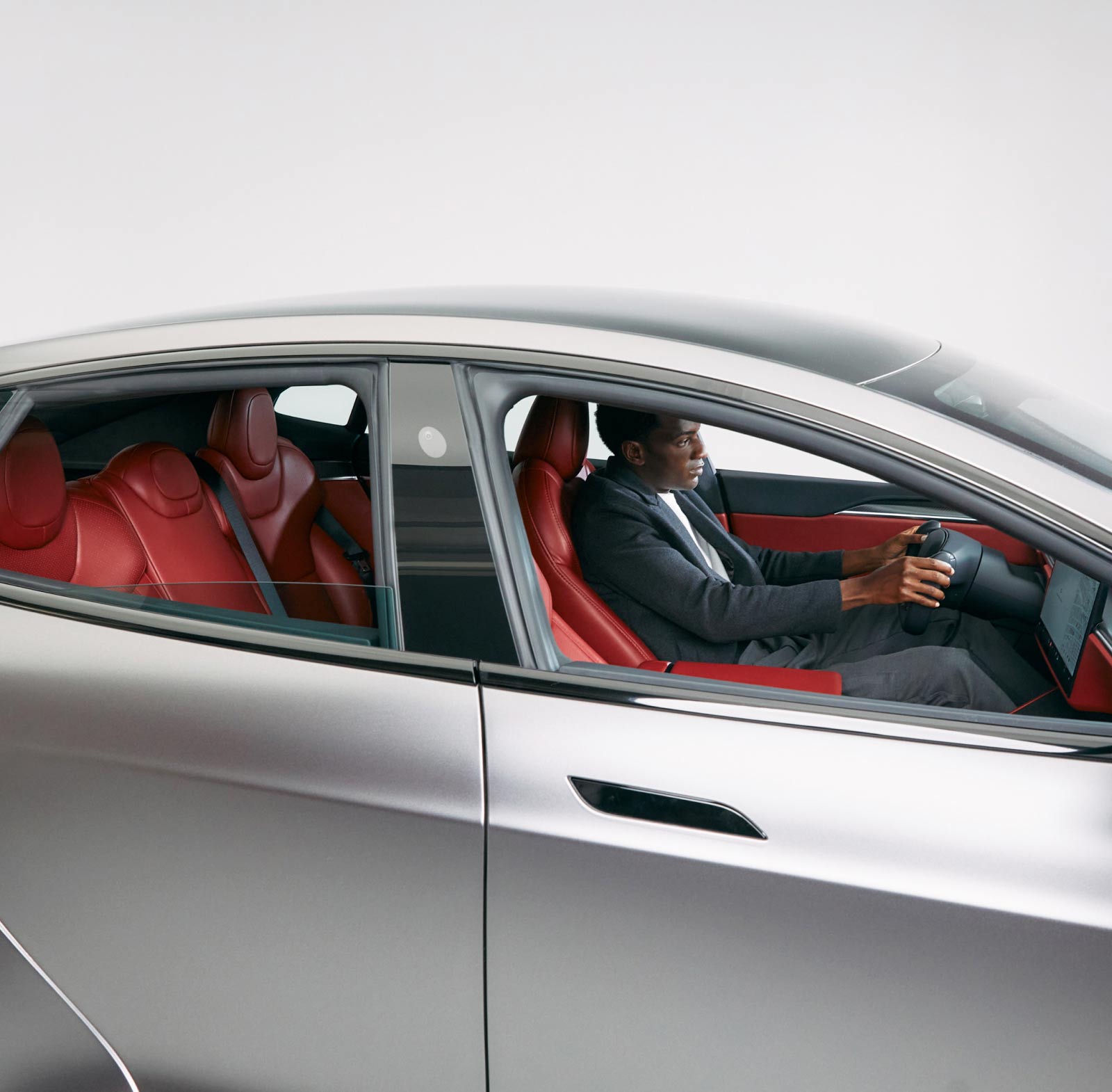Crop of a silver Tesla Model S showing driver and custom Serrano Red interior