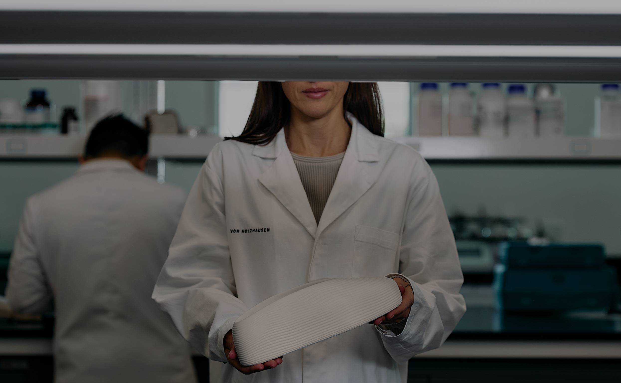 von Holznausen chemist in a lab coat holding a shoe made of Liquidplant in the laboratory
